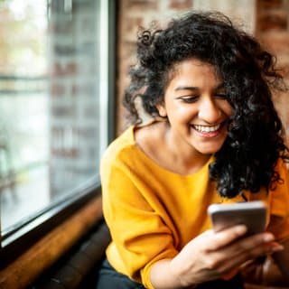 Pilot community member smiling at her phone in a cafe